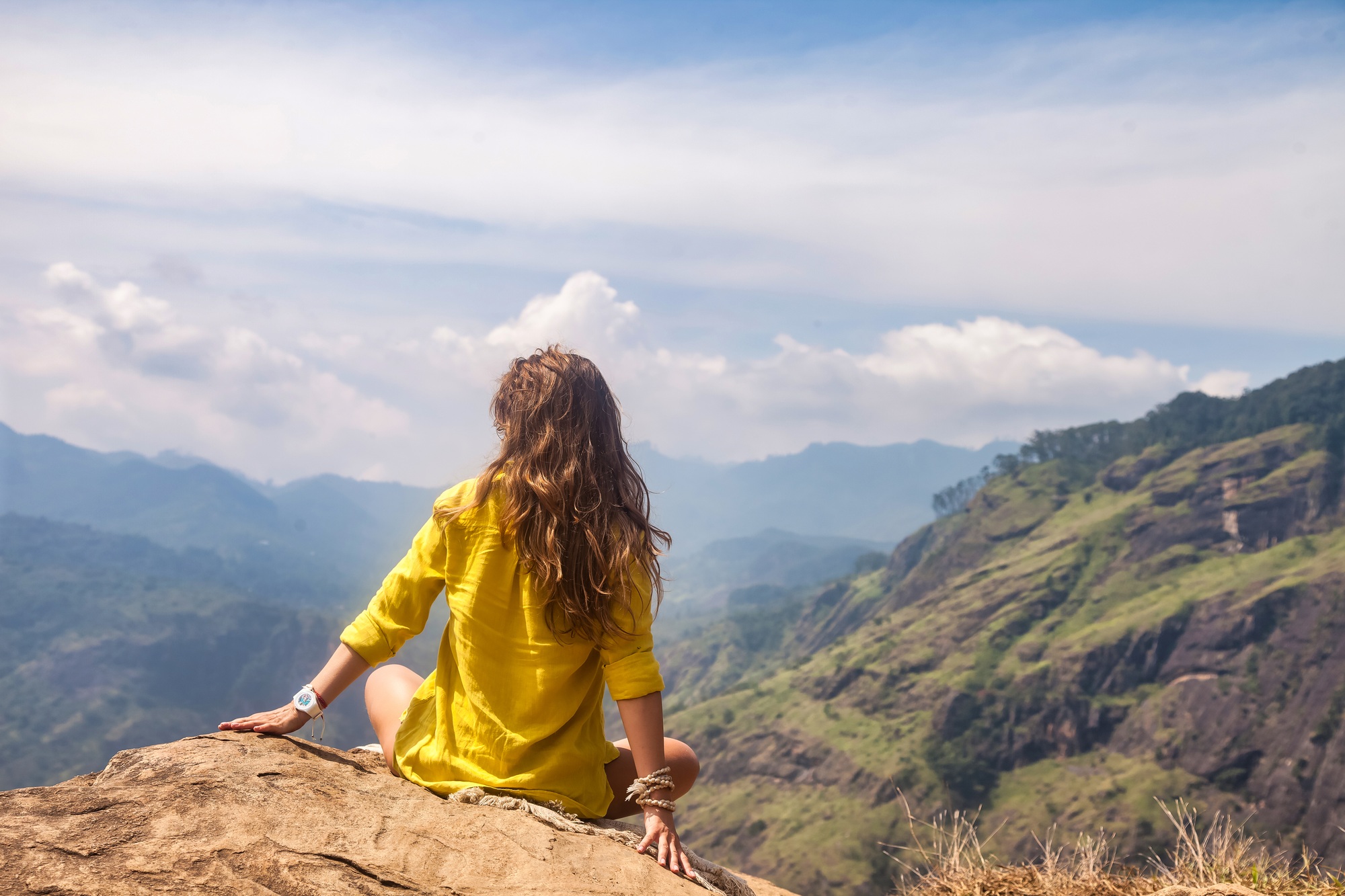 Rear view of lady in yellow jacket sitting at landmark nature background, Sri Lanka, Ella